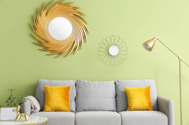 Oturma odasının iç tarafında yastıkları ve kahve masası olan rahat gri bir kanepe.