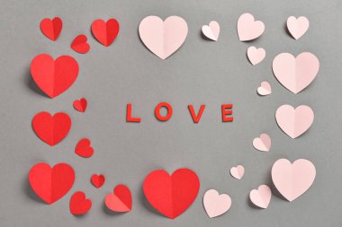 Gri arka planda kırmızı ve pembe kağıt kalplerle romantik kompozisyon. Sevgililer Günü.