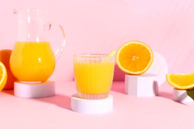 Cam ve pembe arka planda taze portakal suyuyla dekoratif podyumlar