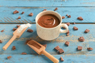 Mavi ahşap arka planda bir fincan lezzetli erimiş çikolata.
