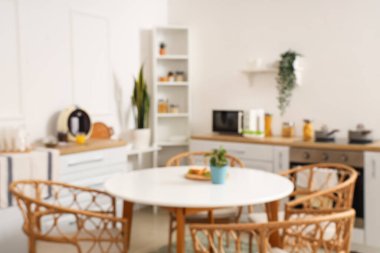 Yeşil bitkilerle, tezgahlarla ve yemek masalarıyla aydınlık mutfağın bulanık görüntüsü