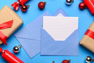 Zarflı boş kağıt, Noel süsü ve mavi arka planda hediyeler. Noel Baba 'ya mektup