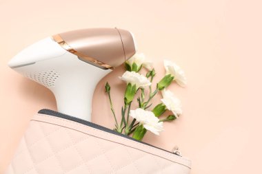 Renkli arka planda modern fotoepilatör ve karanfil çiçeklerine sahip kozmetik çanta, yakın plan