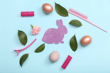 Mavi arka planda Paskalya yumurtası ve kağıt tavşanlı kuaför aksesuarları.