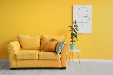 Şık oturma odasının içinde rahat bir kanepe, resim ve çiçek var.