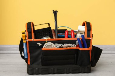 Sarı duvarın yanında yerde elektrikli alet çantası var.