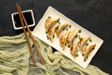 Kızarmış Japon gyoza tabağı ve siyah arka planda soya sosu.