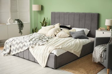 Yatağı, komodinleri, koltuğu ve lambası olan modern yatak odası.