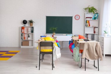 Kara tahtası, masası ve raf ünitesi olan sınıfın içi