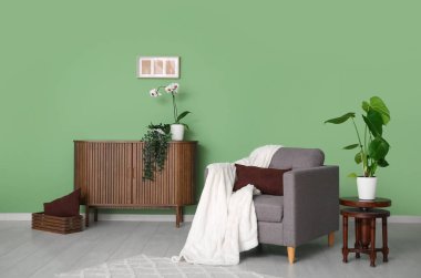 Oturma odasında minderli, ekoseli ve çekmeceli koltuk ve orkide çiçekli.