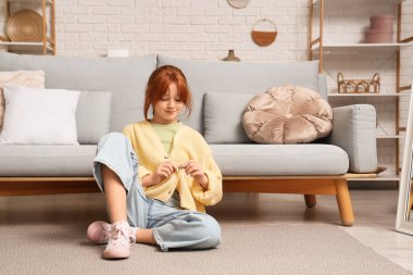 Evde sarı hırka ilikleyen genç kız.