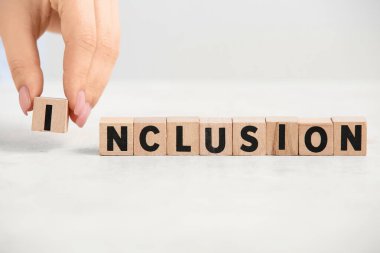 Beyaz masa üzerinde kelime INCLUSION ile kadın el ve küpleri