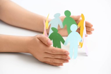 Beyaz masada kağıt insan figürleri olan kadın eller, yakın plan. Katılım kavramı