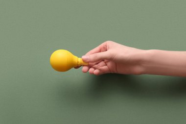 Yeşil arka planda sarı ampullü bir kadın eli.