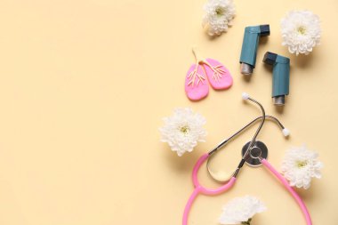 Astım spreyleri, steteskop, akciğer biblosu ve bej arka planda kasımpatı çiçekleri.