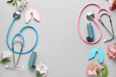 Beyaz arka planda stetoskoplu astım spreyleri, kağıt akciğerler ve alstromerya çiçekleri.