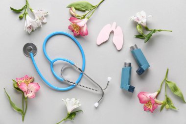 Steteskoplu astım spreyleri, beyaz arka planda kağıt akciğerler ve alstromerya çiçekleri.
