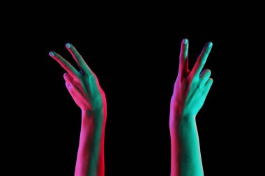 Koyu arkaplanda zafer jesti gösteren tonlanmış kadın elleri