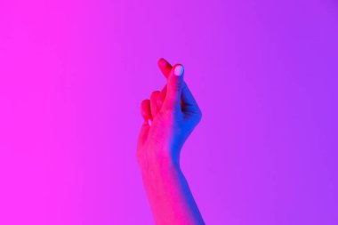 Kadın eli pembe arka planda kalp hareketi yapıyor.