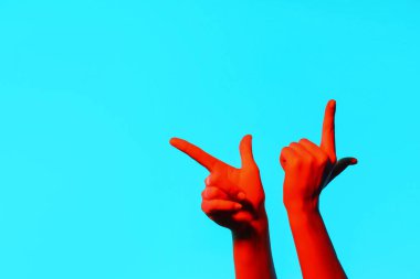 Mavi arka planda bir şeye işaret eden tonlanmış kadın elleri.