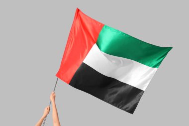 Hafif arkaplanda BAE bayrağı sallayan kadın eller