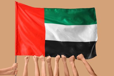 Bej arka planda sıkılmış yumruklar ve BAE bayrağı olan birçok el