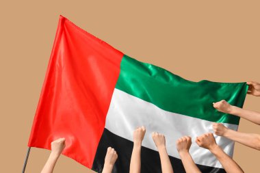 Bej arka planda sıkılmış yumruklar ve BAE bayrağı olan birçok el
