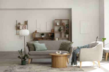 Koltuklu rahat kanepe, sehpa ve oturma odasındaki beyaz duvarın yanındaki raf üniteleri.