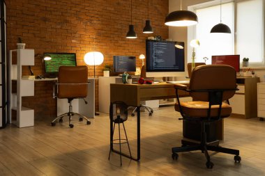 Akşamları masaları ve parlak lambaları olan programcı ofisinin içinde.