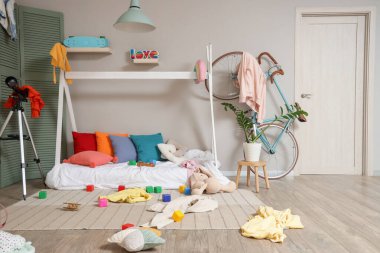 İçinde yatak, bisiklet ve dağınık giysiler olan dağınık çocuk odası.