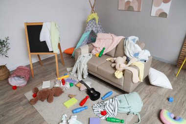 Kanepe, karatahta ve dağınık giysilerle dolu dağınık çocuk odasının içi.