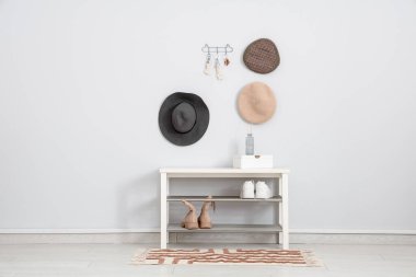 Ayakkabı rafları, şapkalar ve anahtarlar beyaz duvarda asılı olan şık bir salonun içinde.