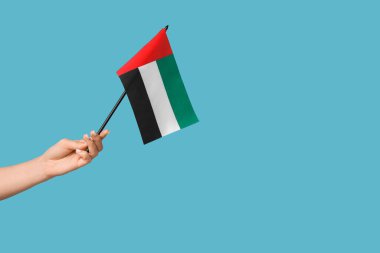 Mavi arka planda BAE bayrağı olan kadın eli