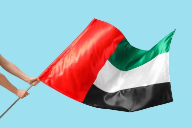 Mavi arka planda bayrak sallayan kadın elleri