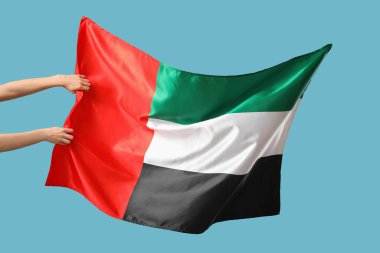 Mavi arka planda BAE bayrağı sallayan kadın eller