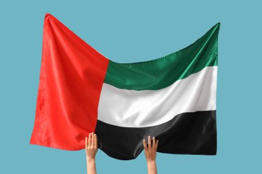 Mavi arka planda BAE bayrağı olan kadın eller