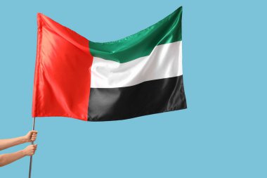 Mavi arka planda bayrak sallayan kadın elleri