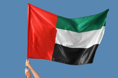 Mavi arka planda bayrak sallayan kadın elleri