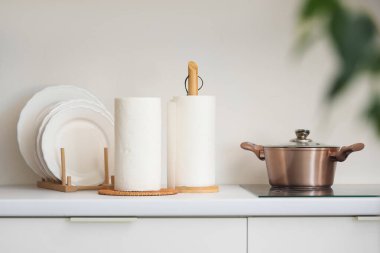 Mutfakta elektrikli sobanın yanında tabakları olan kağıt havlu ruloları.