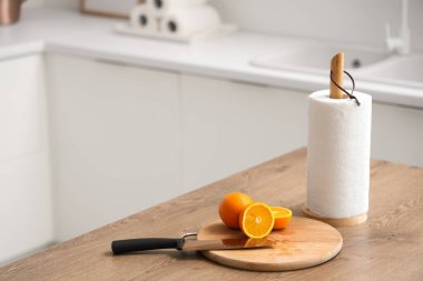 Mutfaktaki masada üzerinde bıçak, portakal ve rulo kağıt havlu olan tahta.