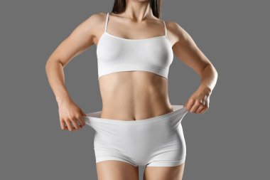 Gri arka planda beyaz iç çamaşırlı güzel bir kadın.