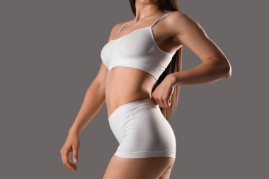 Gri arka planda beyaz iç çamaşırlı güzel bir kadın.