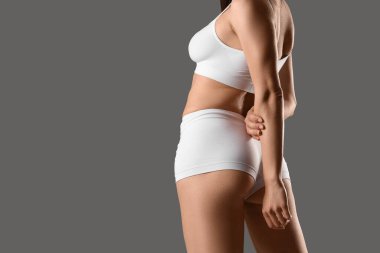 Gri arka planda beyaz iç çamaşırlı güzel bir kadın.