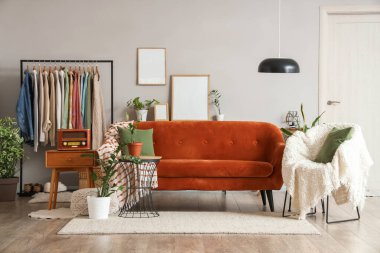 Elbise askısı, kanepesi ve koltuğu olan bir oturma odası.