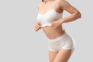 Beyaz arka planda poz veren şık iç çamaşırlı güzel bir kadın.