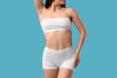 Mavi arka planda beyaz iç çamaşırlı güzel bir kadın.