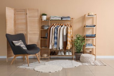 Elbise askısı, raf ünitesi ve koltuğu olan soyunma odasının içinde.