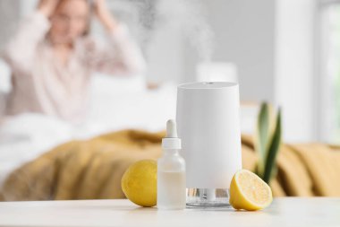 Yatak odasındaki uyanık kadına karşı limonlu ve yağlı hava nemlendirici, yakın plan.