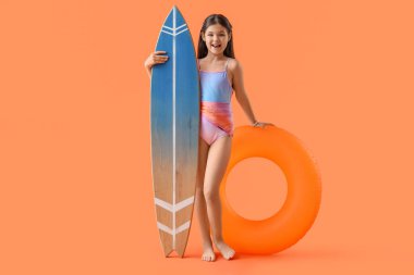 Yüzme yüzüğü ve turuncu arka planda sörf tahtası olan tatlı bir kız.