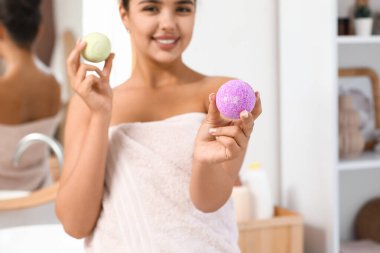 Banyoda aynanın yanında banyo bombaları taşıyan güzel genç bir kadın.